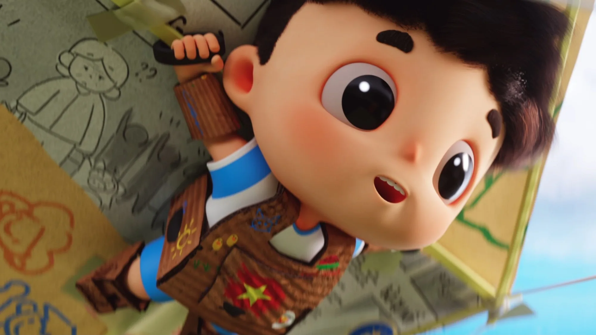 A boy in cardboard armour clings to a giant paper kite covered in children’s drawings.